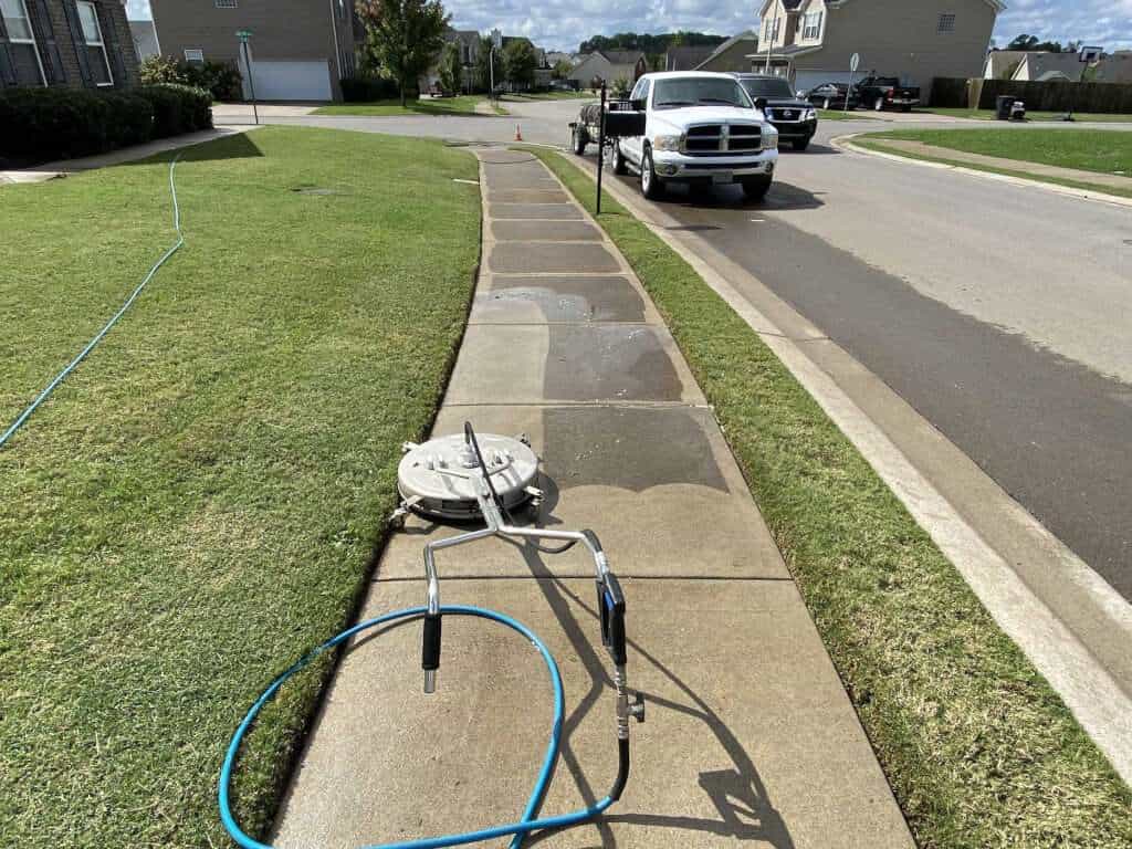 technician using surface cleaner on concrete- JB Power Wash