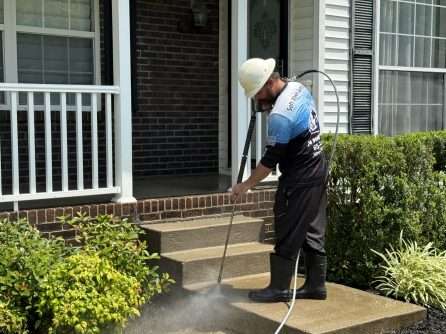 Technician soft washing house siding and trim